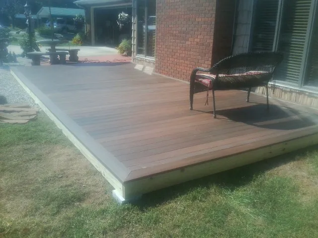 New wood deck and wicker chair beside a brick house in Calhoun
